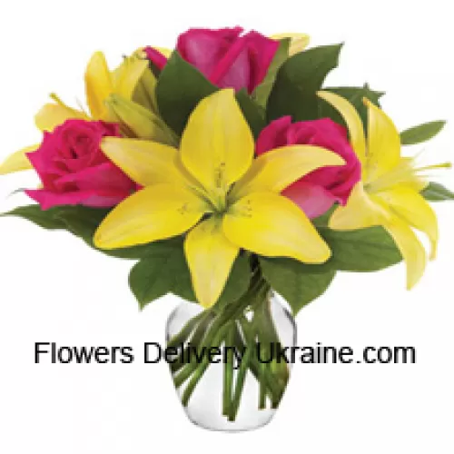 Roses roses et lys jaunes avec des remplisseurs saisonniers disposés magnifiquement dans un vase en verre