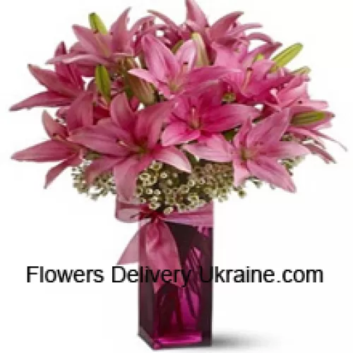 Beaux lys roses avec quelques fougères dans un vase en verre